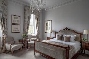 a bedroom with a large bed and a chandelier at Bailbrook House Hotel, Bath in Bath