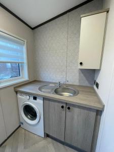 a bathroom with a sink and a washing machine at Brackencroft Lodge with Hot Tub in York