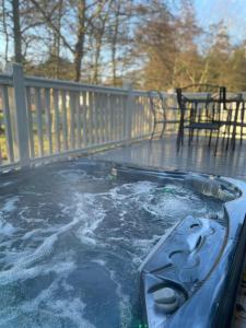 a hot tub on a deck with a table at Brackencroft Lodge with Hot Tub in York