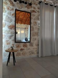 a mirror on a stone wall with a table in a room at Vigla Villas in Volímai