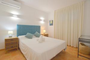 a bedroom with a white bed with a blue headboard at Seafront Apartment in Magaluf in Magaluf