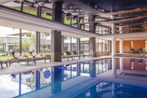 a swimming pool in a building with people sitting on chairs at Rivage Hôtel & Spa Annecy in Annecy