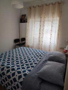 a bedroom with a blue and white bed and a curtain at CasaBarreiro in Barreiro