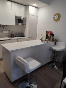 a white kitchen with a counter and two stools at CasaBarreiro in Barreiro