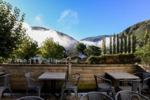 a patio with tables and chairs with mountains in the background at Logis Hôtel du Chêne in Itxassou