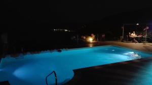 a swimming pool at night with people sitting at a table at Oroverde in Bergeggi