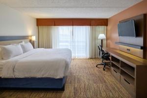 a hotel room with a bed and a desk with a television at Wyndham El Paso Airport and Water Park in El Paso
