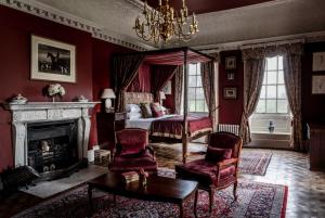 a bedroom with a canopy bed and a fireplace at Chilston Park Hotel in Lenham