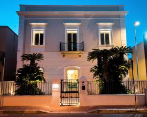 een wit huis met twee palmbomen ervoor bij La Corte del Fante in Marsala