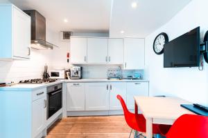 una cocina con armarios blancos y una mesa con sillas rojas en 72a High Street, en Southwold