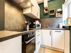 uma cozinha com armários brancos e paredes verdes em Endearing Holiday Home in Noordwijkerhout with Garden BBQ em Noordwijkerhout