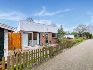 uma casa de tijolos com uma cerca ao lado de uma estrada em Endearing Holiday Home in Noordwijkerhout with Garden BBQ em Noordwijkerhout