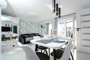 a dining room and living room with a white table and chairs at Apartamenty Prestige in Łeba