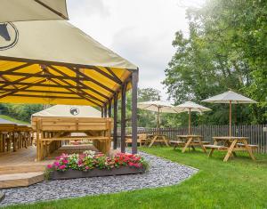 un gruppo di tavoli da picnic e ombrelloni in un cortile di The Nags Head Inn ad Abercych