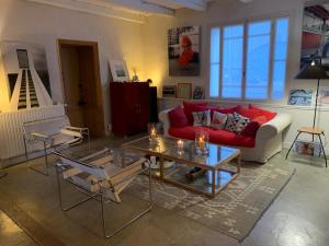 sala de estar con sofá rojo y mesa en Maison Face au Soleil en Le Bois-Plage-en-Ré