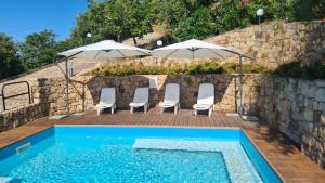 a pool with chairs and umbrellas on a wooden deck at CH Exclusive Apartments in Cefalù
