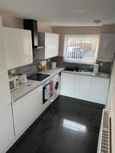 a kitchen with white cabinets and a sink and a dishwasher at Large spacious 3 bedroom house Westerhope in Lemington