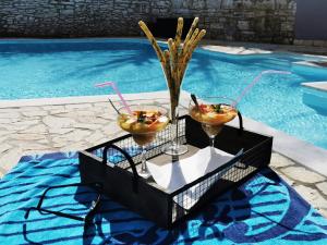 a tray with two drinks on a table next to a swimming pool at Casa della Grofica in Kringa