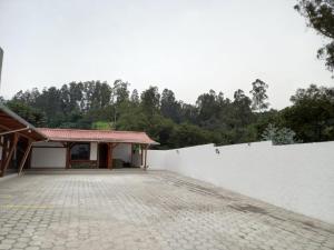 a building with a white wall and a brick driveway at Hostal Aventura in Quito