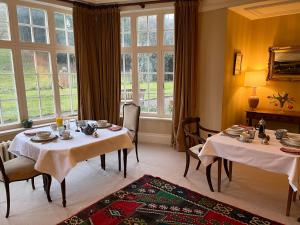 two tables and chairs in a room with windows at Yearle House in Wooler