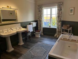 a bathroom with two sinks and a tub and a window at Yearle House in Wooler