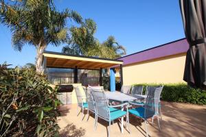 une table et des chaises assises sur une terrasse dans l'établissement Nautilus Apartments Merimbula, à Merimbula