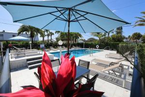 um guarda-sol azul sobre uma mesa e cadeiras ao lado de uma piscina em Tropic Isle Beach Resort em Deerfield Beach