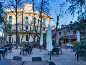 a courtyard with tables and umbrellas in front of a building at Els Jardins De La Martana in Besalú