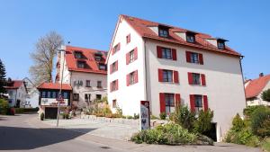 ein weißes Gebäude mit rotem Dach neben einer Straße in der Unterkunft Hotel Gasthof Adler in Ulm