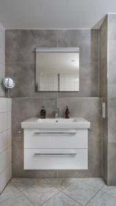 a bathroom with a white sink and a mirror at Family Ferienhaus Ennens in Rhauderfehn
