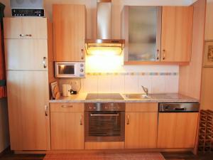 a kitchen with wooden cabinets and a sink and a microwave at Villa on a courtyard near the ski area in Salzburg in Eben im Pongau