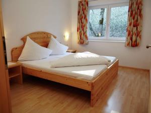 a bedroom with a wooden bed with white pillows and a window at Spacious Apartment with Sauna in F gen in Fügen