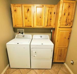 a laundry room with two washes and wooden cabinets at The Greenhouse - 3bed 2bath home in Tahlequah, OK in Tahlequah