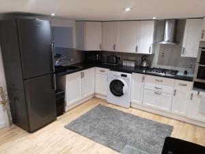 a kitchen with white cabinets and a black refrigerator at High gables Apartment 1 in Paignton