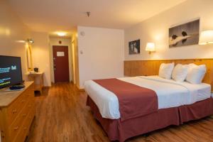 ein Hotelzimmer mit einem Bett und einem Flachbild-TV in der Unterkunft Canadas Best Value Inn- Riverview Hotel in Whitehorse