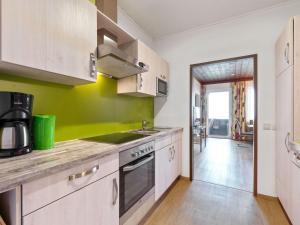 a kitchen with white cabinets and a green wall at Spacious Apartment in Afritz am See near Ski Area in Afritz