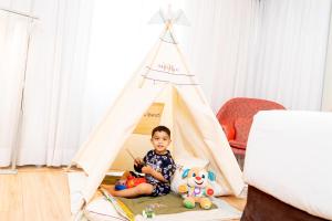 a young boy sitting in a teepee tent at Mercure Sao Paulo Jardins in Sao Paulo