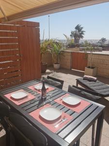 a table with plates and a bottle of wine on a patio at Modern sea view duplex with parking in El Médano