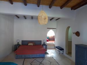 1 dormitorio con 1 cama roja en una habitación blanca en Ourika Timalizène le jardin des délices en Tamzerdirt