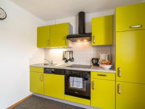 a kitchen with yellow cabinets and a stove at Apartment in Tirol with private garden in Kirchberg in Tirol