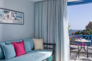 a couch with colorful pillows in a room with a balcony at Veggera Beach Hotel in Perissa