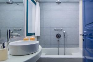 a bathroom with a tub and a sink and a shower at Veggera Beach Hotel in Perissa
