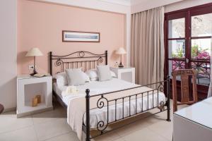 a bedroom with a bed and a chair and a window at Veggera Beach Hotel in Perissa