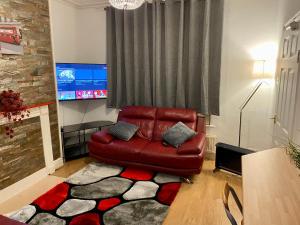 a living room with a red leather couch and a television at SureScape House in Liverpool