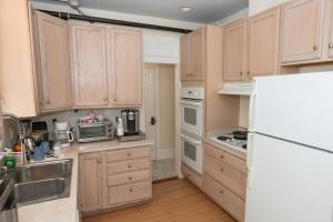 a kitchen with wooden cabinets and a white refrigerator at The Esplanade Guesthouse Mansion in New Orleans