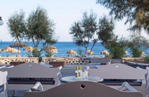a restaurant with tables and chairs and the ocean at Veggera Beach Hotel in Perissa