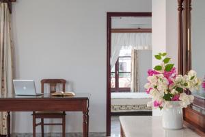 a bedroom with a desk with a laptop and a vase of flowers at Veggera Beach Hotel in Perissa