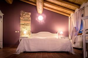 a bedroom with a white bed and a stone wall at Agriturismo Corte Moranda in Novaglie