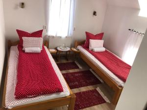 Tünde Vendégház في Viştea: سريرين في غرفة ذات أغطية حمراء وبيضاء