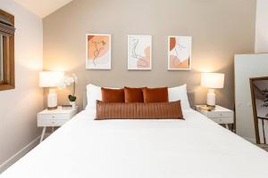 a bedroom with a large white bed with three paintings on the wall at Peaceful 2-bedroom townhome retreat w/wooded view in Galena +30 photos
